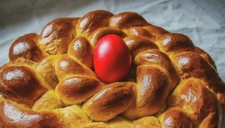 Uskršnja pogača pletenica izbliza sa crvenim uskršnjim jajetom u sredini.