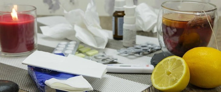 Čaj i limun na stolu pored lekova i papirnih maramica