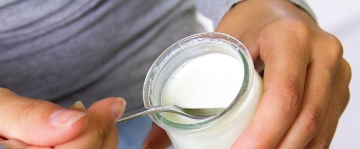 Čovek jede jogurt iz staklene posude
