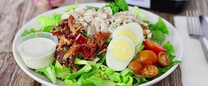 Salata sa jajima i piletinom servirana na belom tanjiru