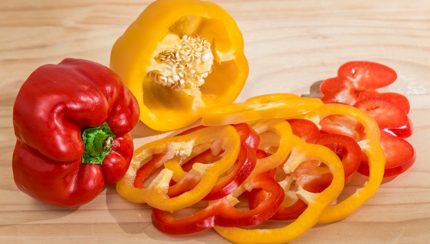 Žuta seckana paprika i crvena paprika na dasci.