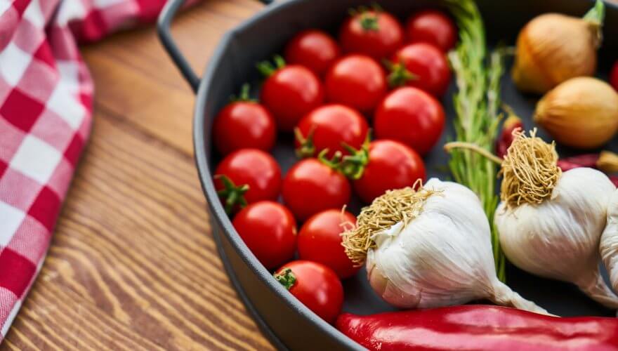 Čeri paradajz, crni i beli luk i paprika u činiji