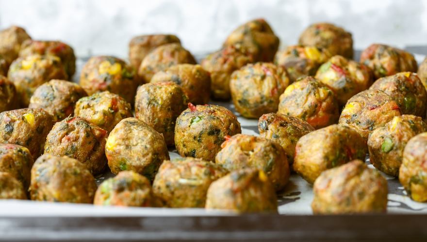 Veganske pljeskavica od tikvica i povrća u tiganju. 